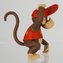 The Diddy Kong figurine displayed on a gaming desk next to a Nintendo console to show its true size context.