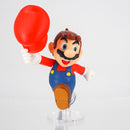 Mario action pose figure displayed on a gaming desk setup next to a console.